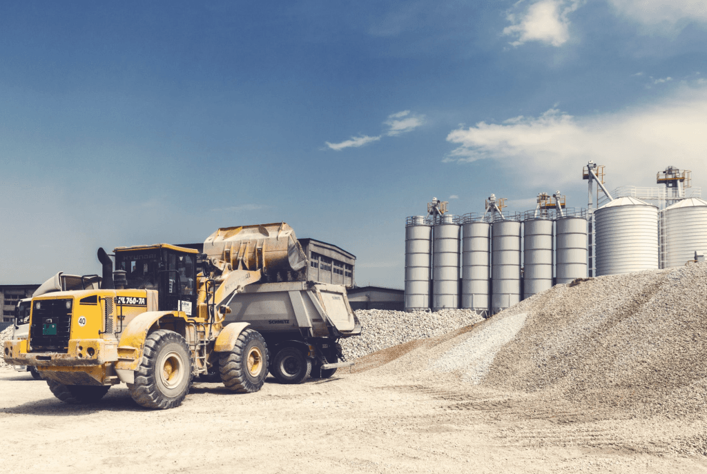A dump truck delivering a load of sand and gravel at a job site.